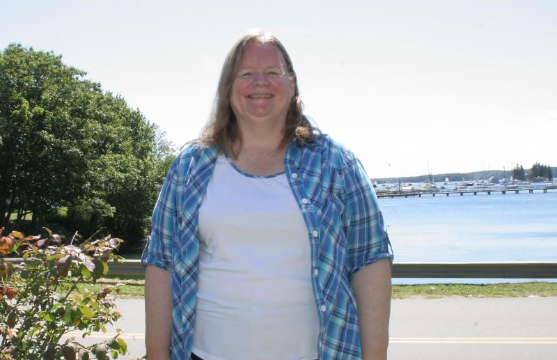 BARBARA ROSS on the front lawn of her Boothbay Harbor home, with the town's footbridge in the background. KEVIN BURNHAM/Boothbay Register